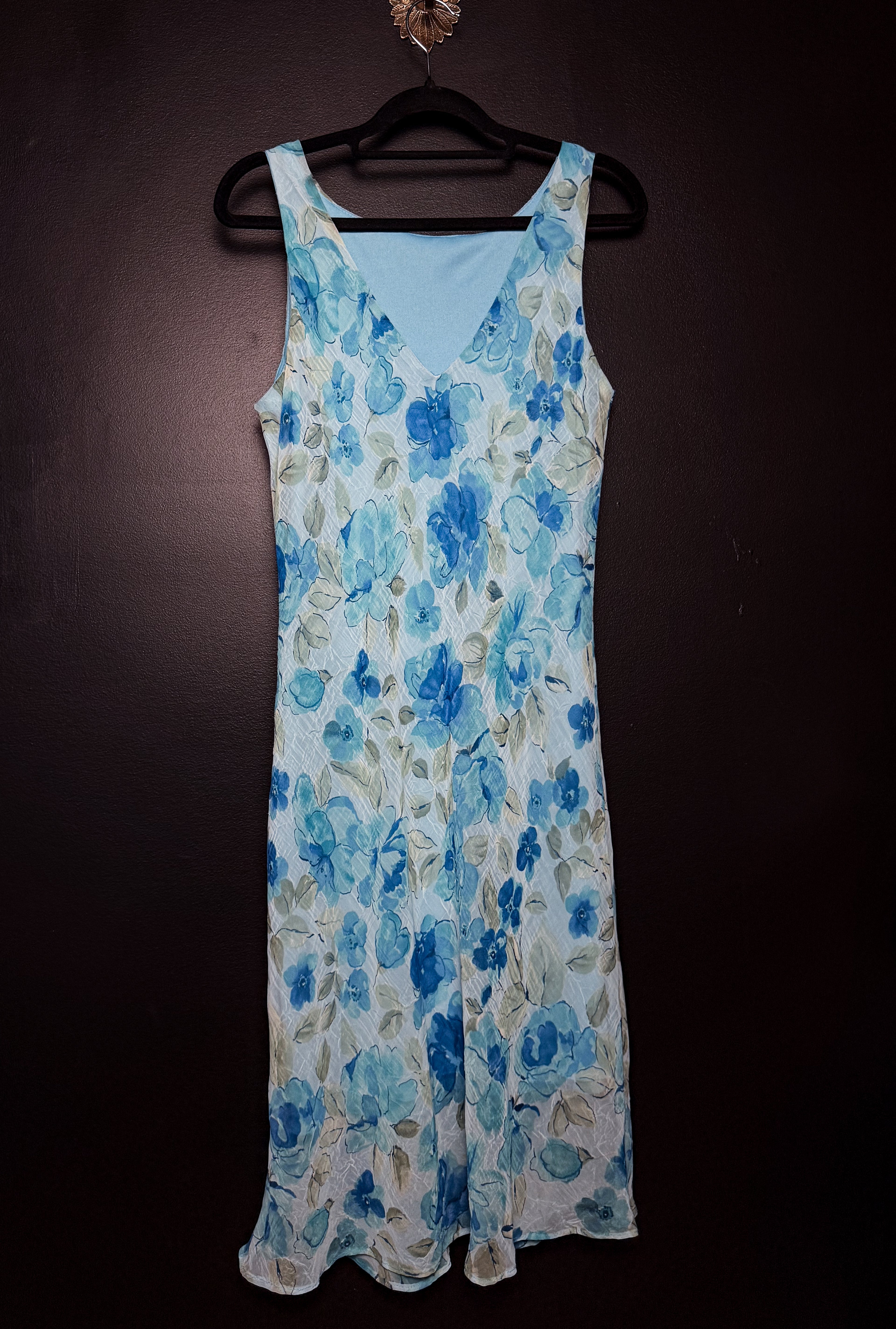 Blue floral dress on a hanger against a dark background