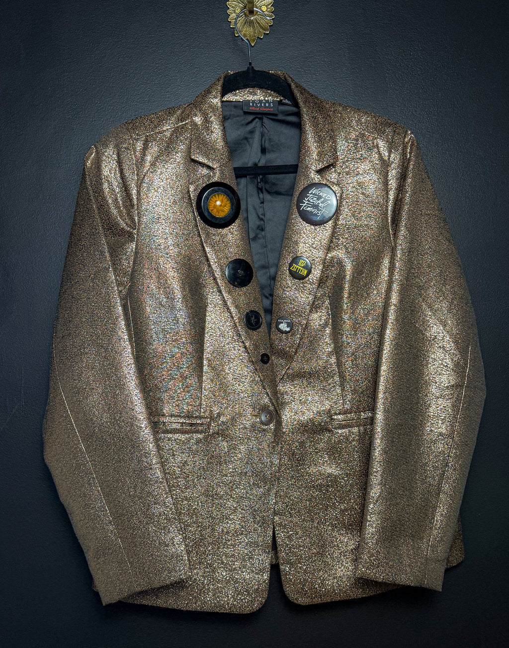 Gold blazer with decorative buttons on a dark background
