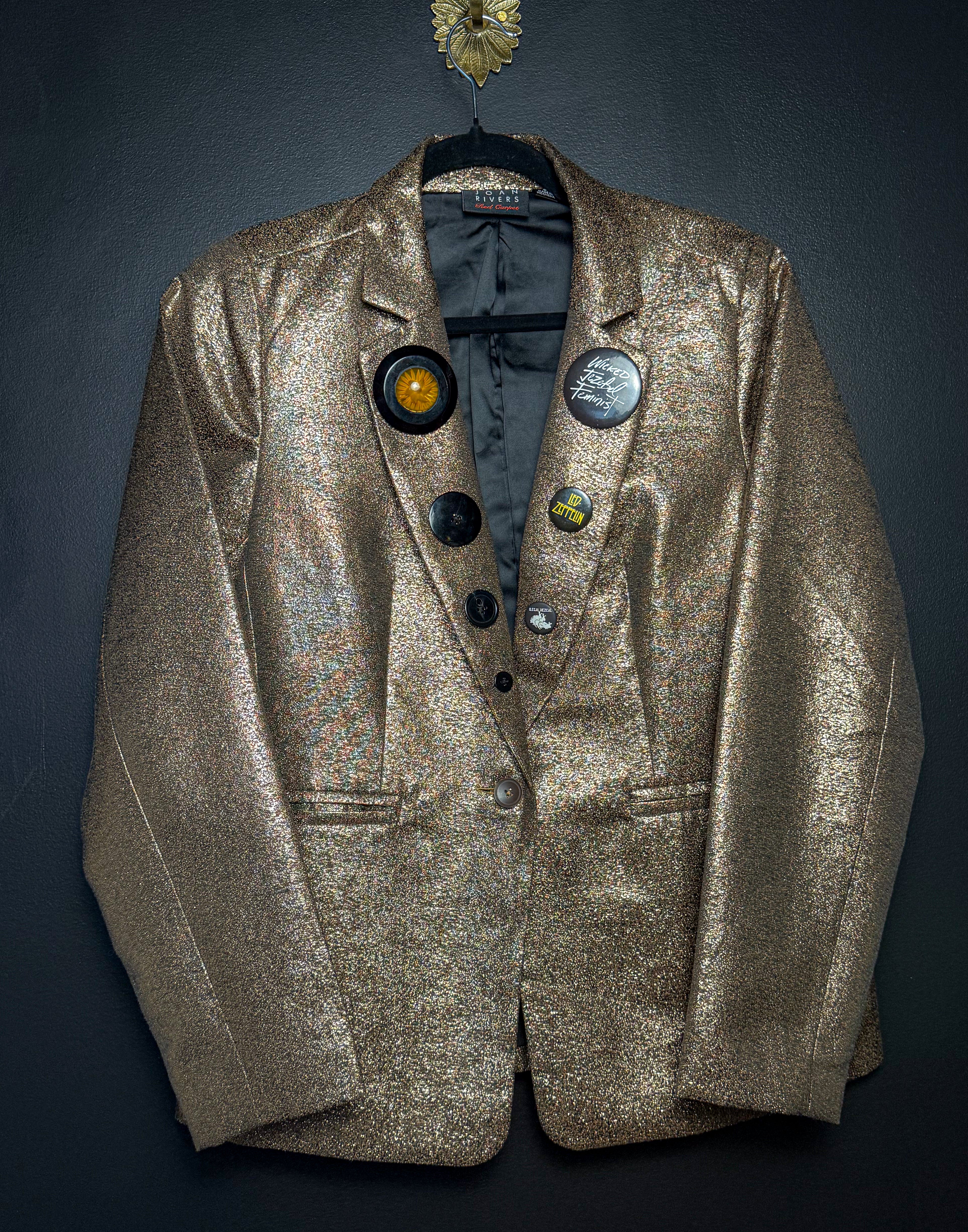 Gold blazer with decorative buttons on a dark background